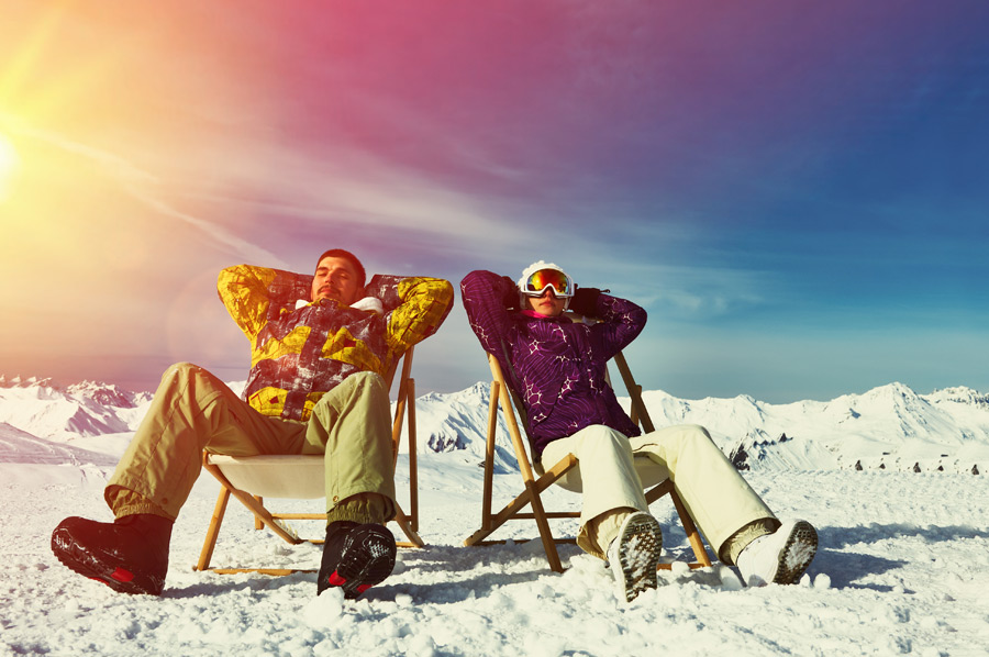 Zwei Menschen sitzen im Stuhl und genießen die Wintersonne in vollen Zügen